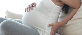 Беременная женщина сидит на диване